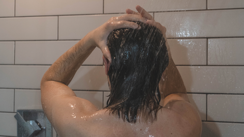 man rinsing hair out in shower after using conditioner.