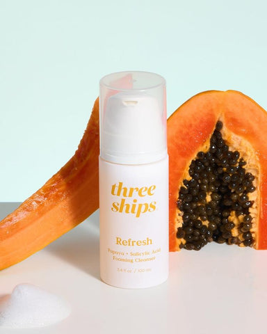 White cleanser bottle in front of papaya 