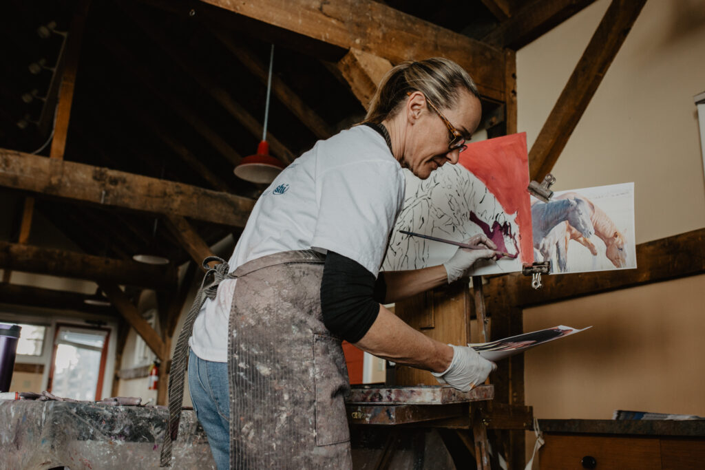 Jill Soukup in her element, painting horses during her annual workshop at Zapata Ranch. Photo by Avery Sass Clark.