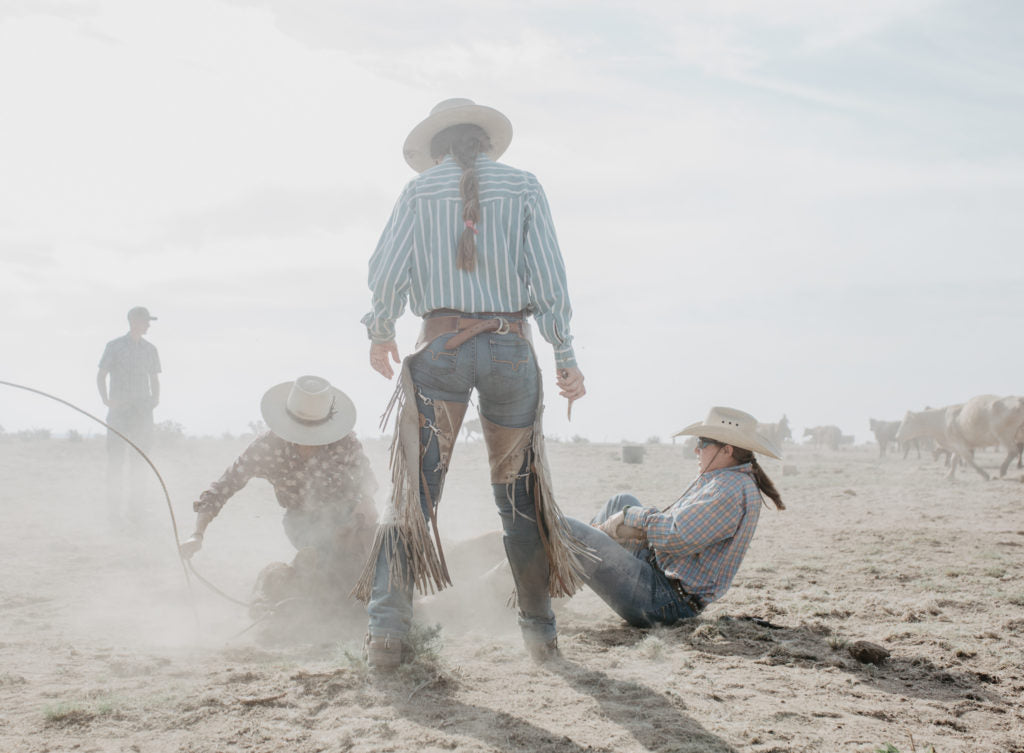 Three cowgirls work together on a calf during a branding on June 15, 2018 at the Chico Basin Ranch.