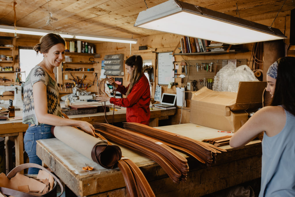 Andrea, Madi and Margo work on belts in the Chico leather shop on August 16, 2018.