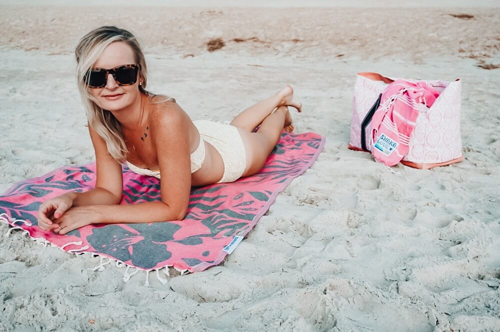 Happy woman enjoying a relaxing moment at the beach on a sand-resistant Turkish beach towel