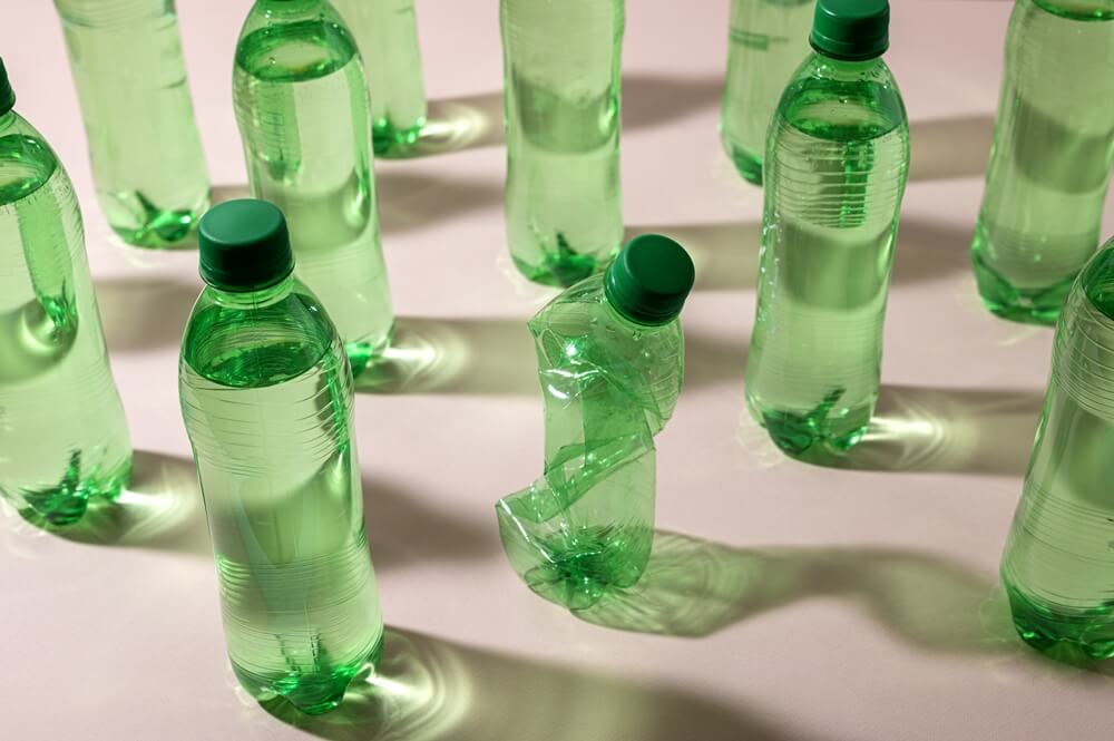 High-angle green plastic bottle arrangement, showing how important to reduce the use of single-use plastics to reduce water pollution