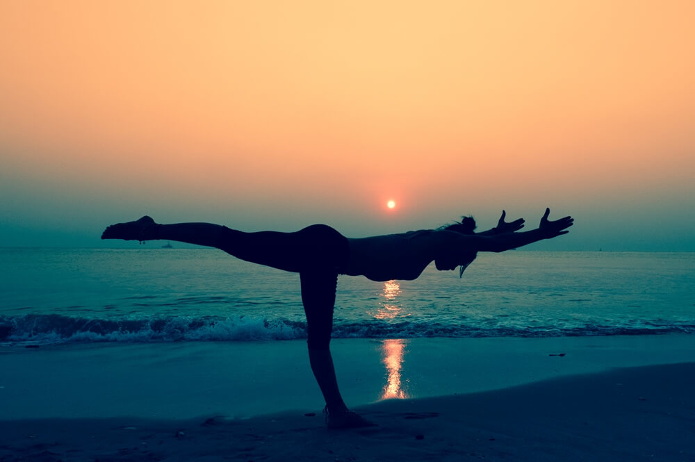 Woman stretching her body with yoga poses near a beach