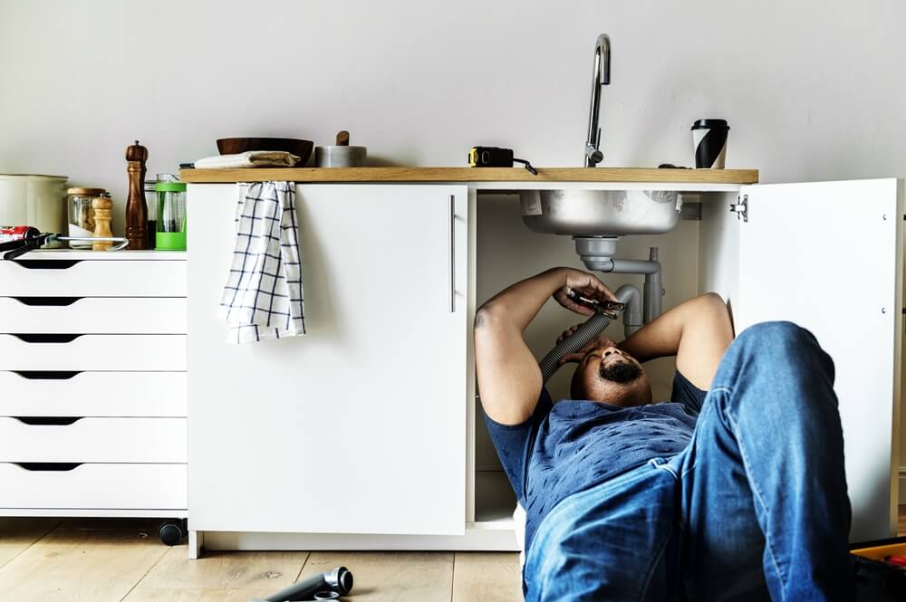 Man fixing the kitchen promptly to stop wasting water