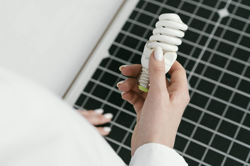 High-angle hand-holding eco lightbulb to conserve energy at home