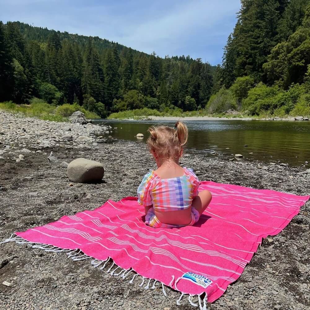 Little girl sits sprawled out on a vibrant Turkish towel, using this colorful Turkish towel as her blanket