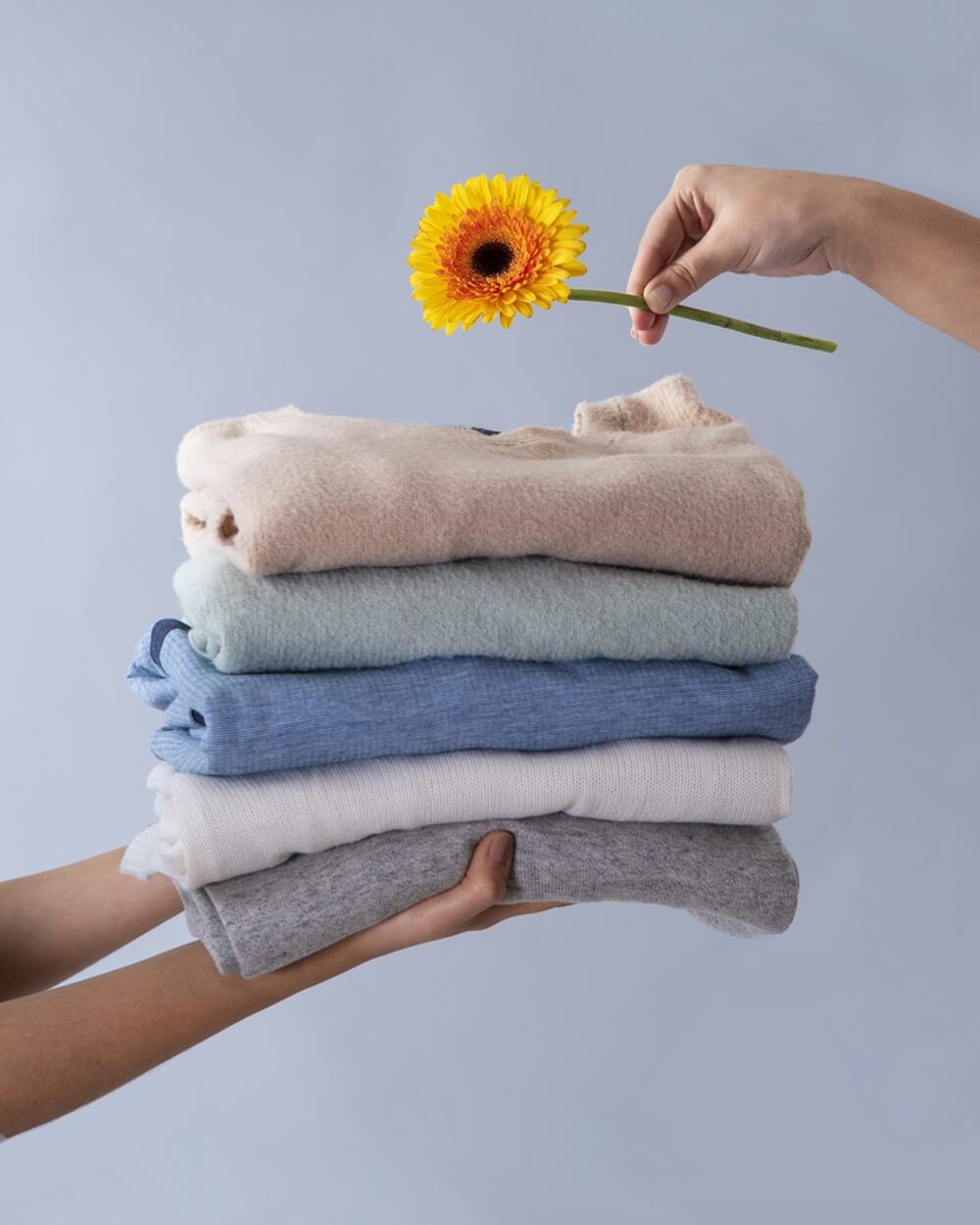 side-view of two people holding clothes with a flower, using eco-friendly products to keep their clothes clean and fresh while protecting the planet