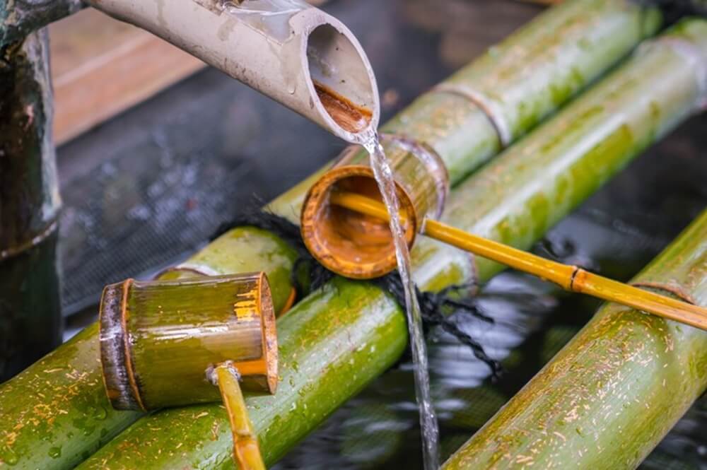 Water pouring out of a bamboo pipe between two bamboo poles