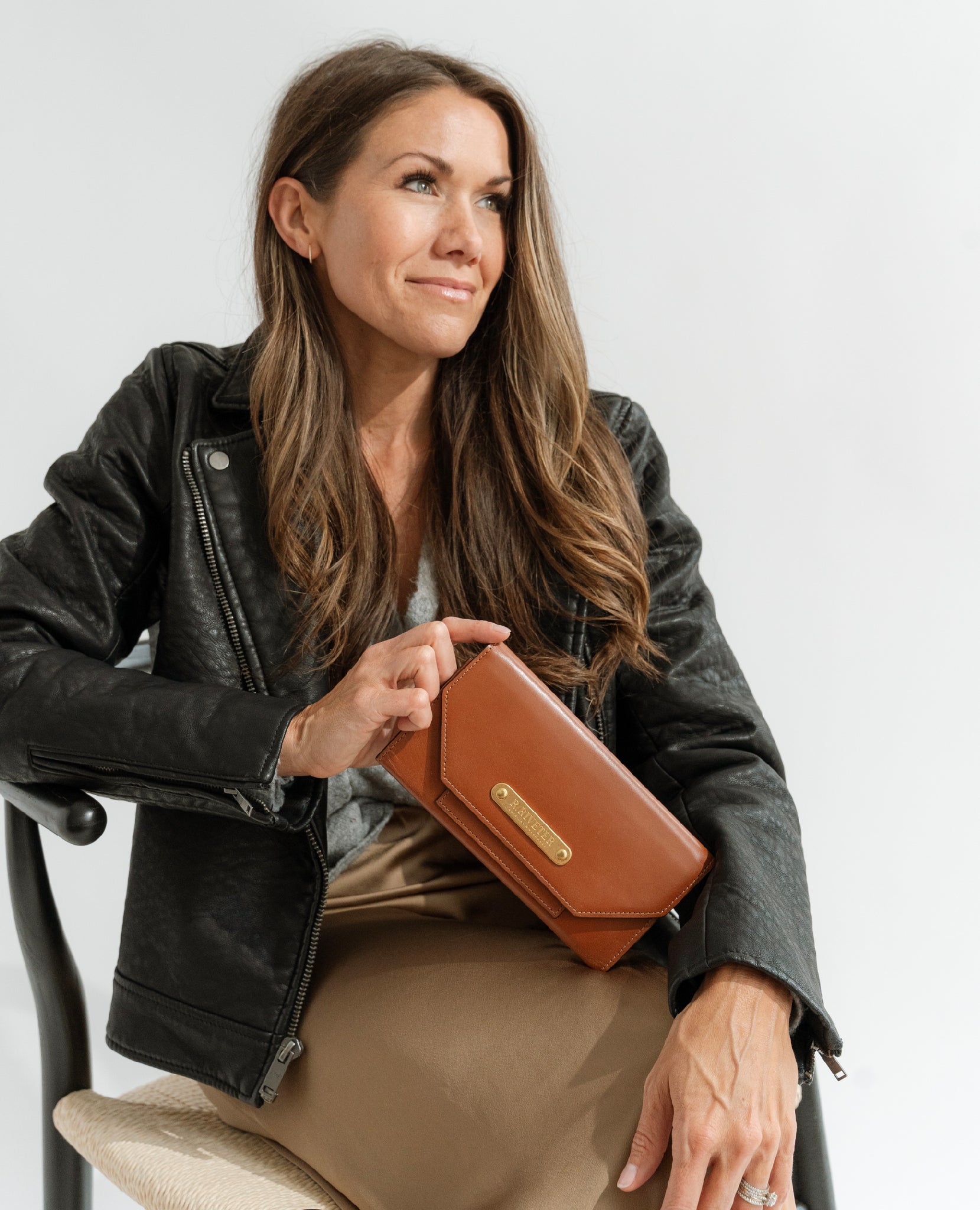 woman sitting and holding large premium leather tan wallet