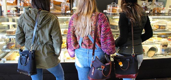 three girls carrying R. Riveter bags at the store