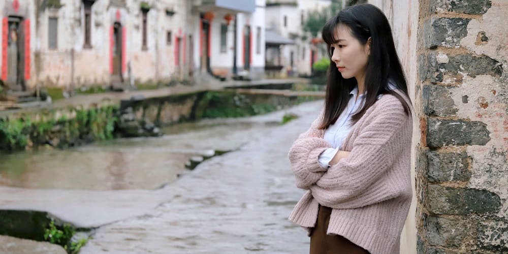 Femme triste qui prend l'air devant chez elle