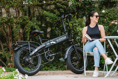 Smiling woman sitting beside her electric bike outdoors