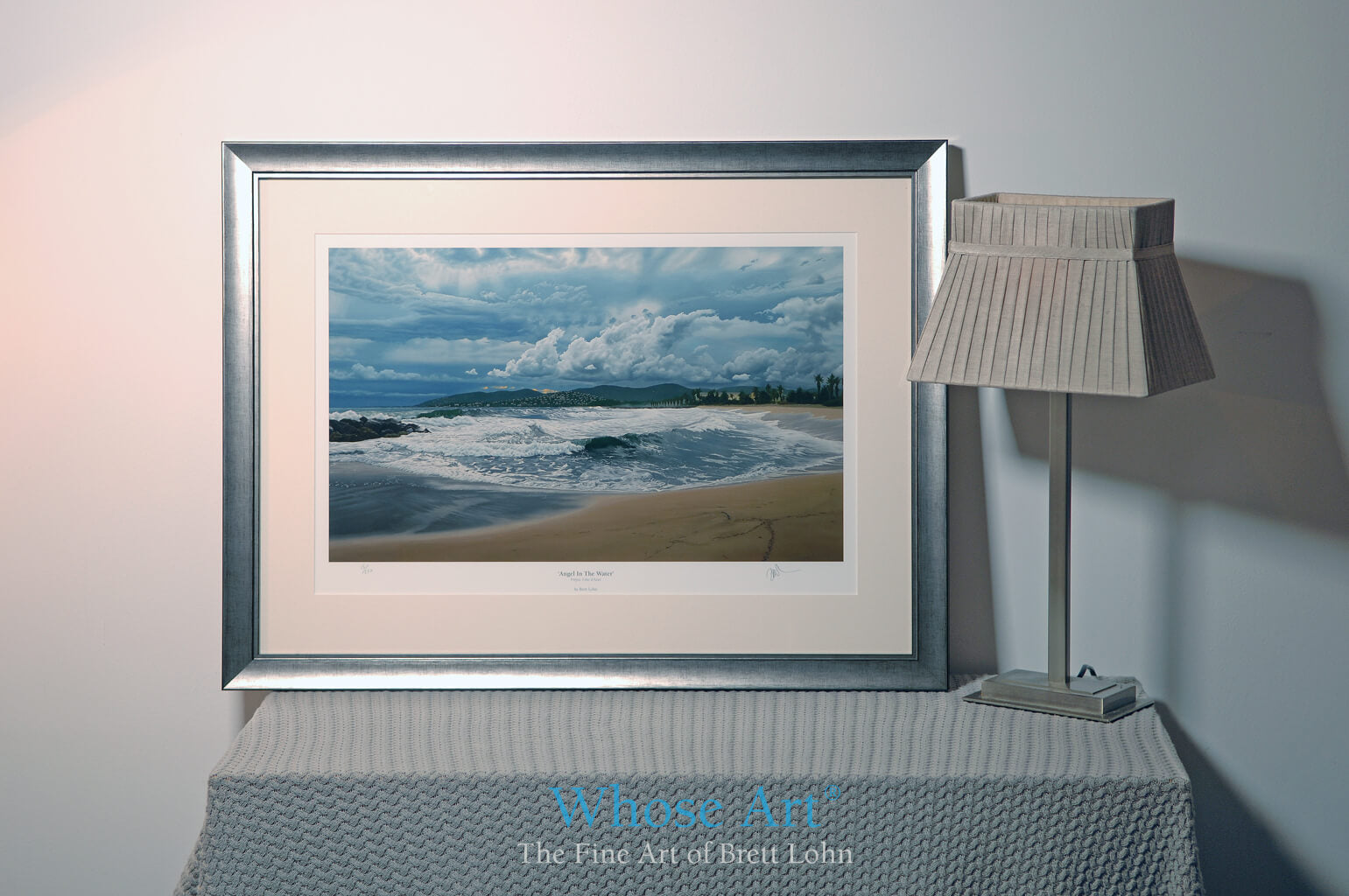 Framed painting of a stormy seascape. Leaning on a table by a lamp