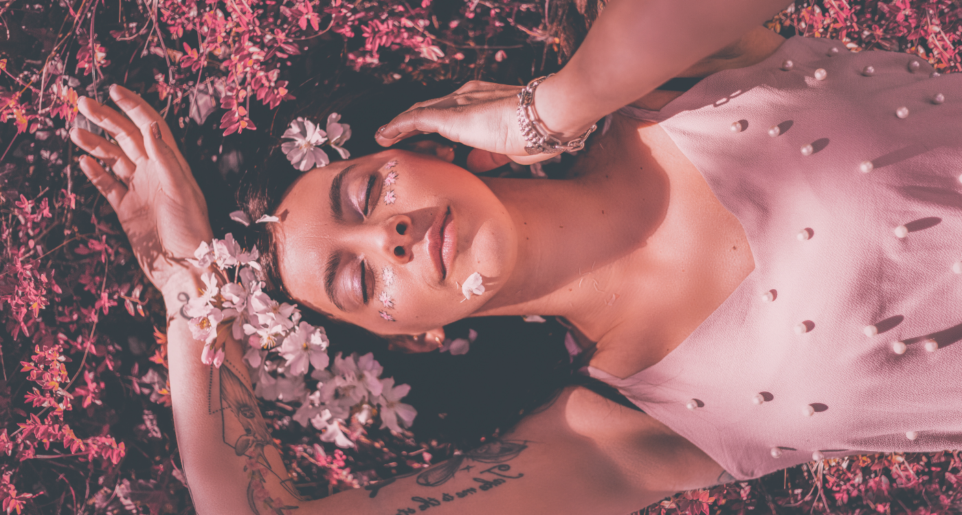 woman laying in bathtub surrounded by intentional things like flowers and crystals