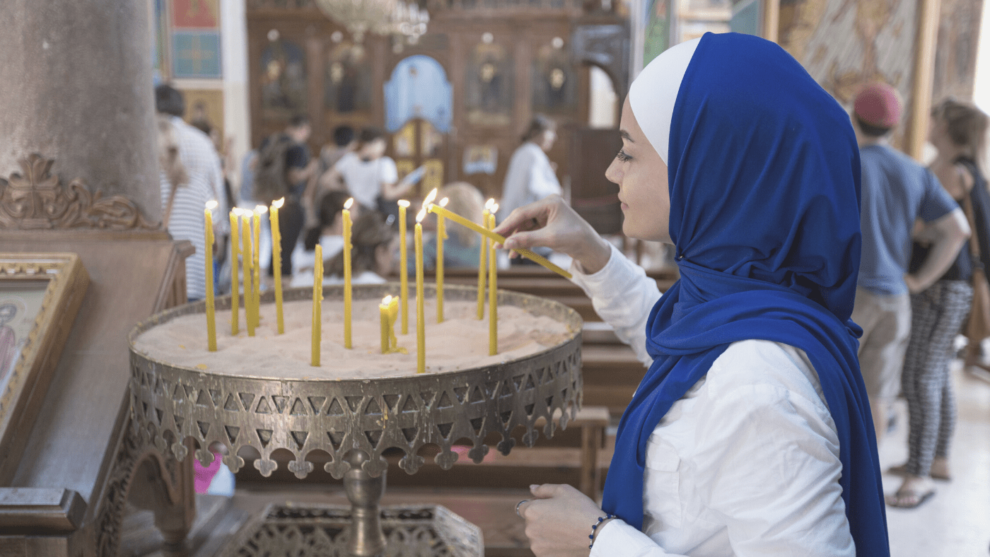 woman lighting spiritual candle in place of worship