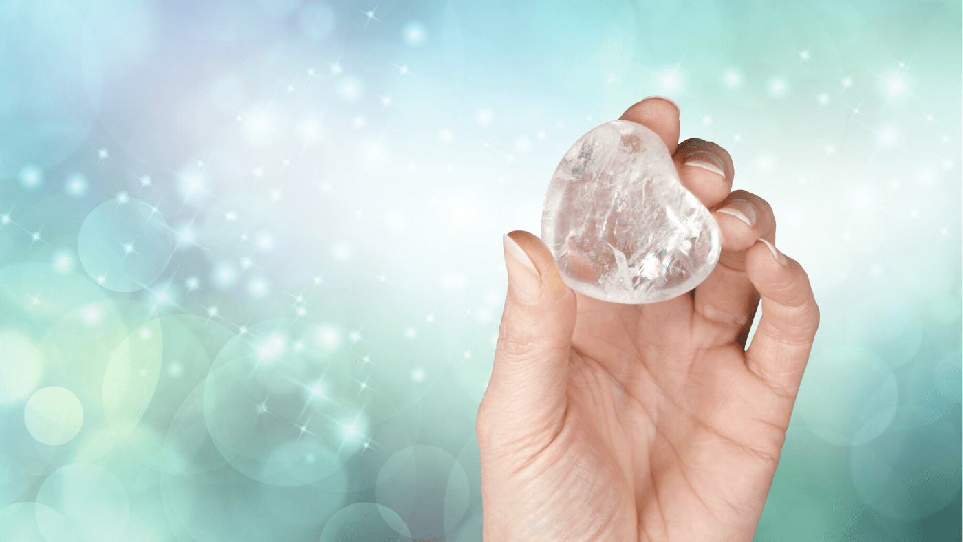 hand holding a clear quartz crystal on metaphysical spiritual background