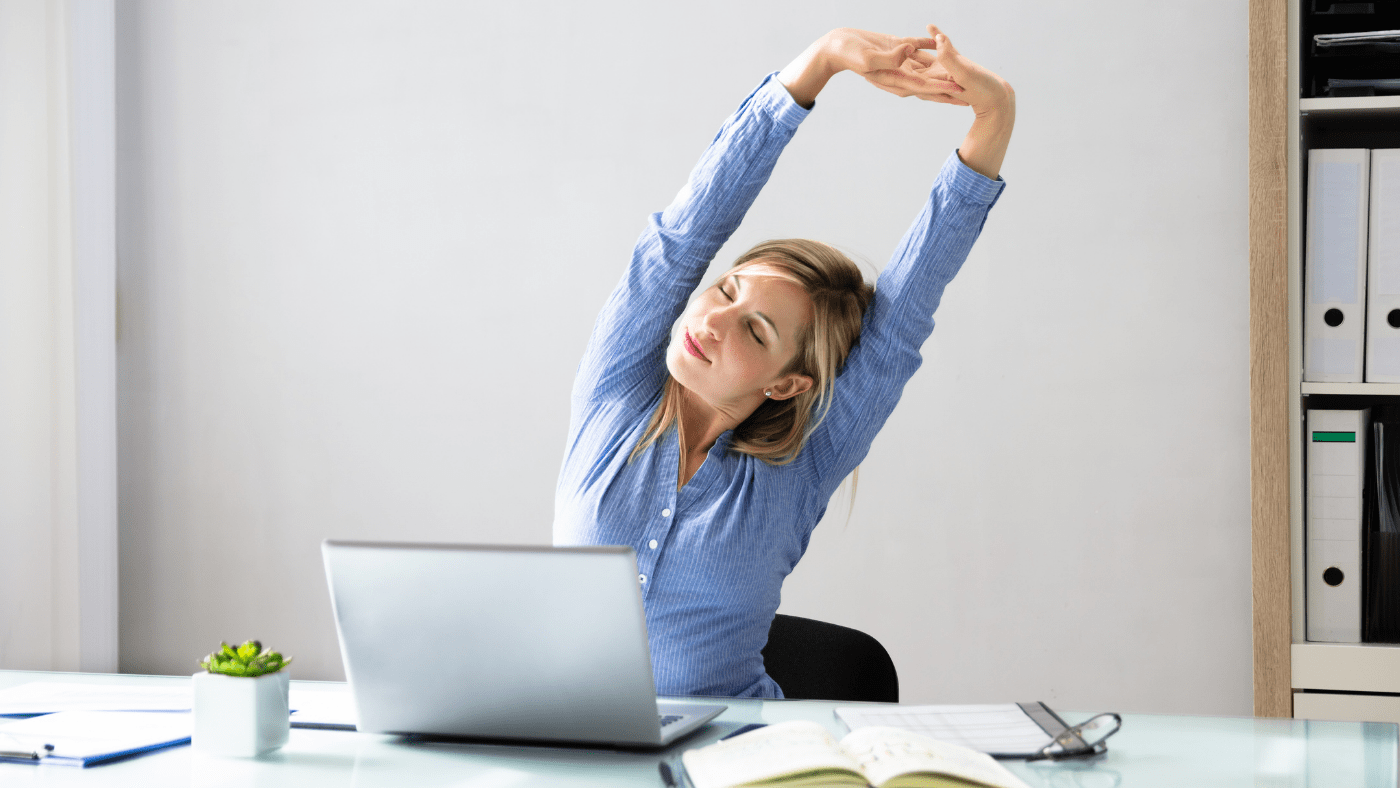 woman stretching at desk as a self care practice as recommended by Nefertem