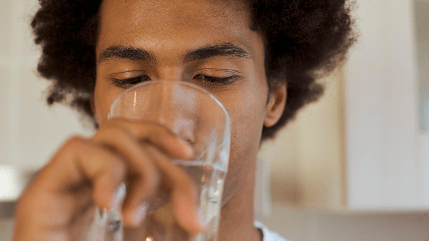 man drinking water out of glass as recommended by Nefertem Intention Skincare