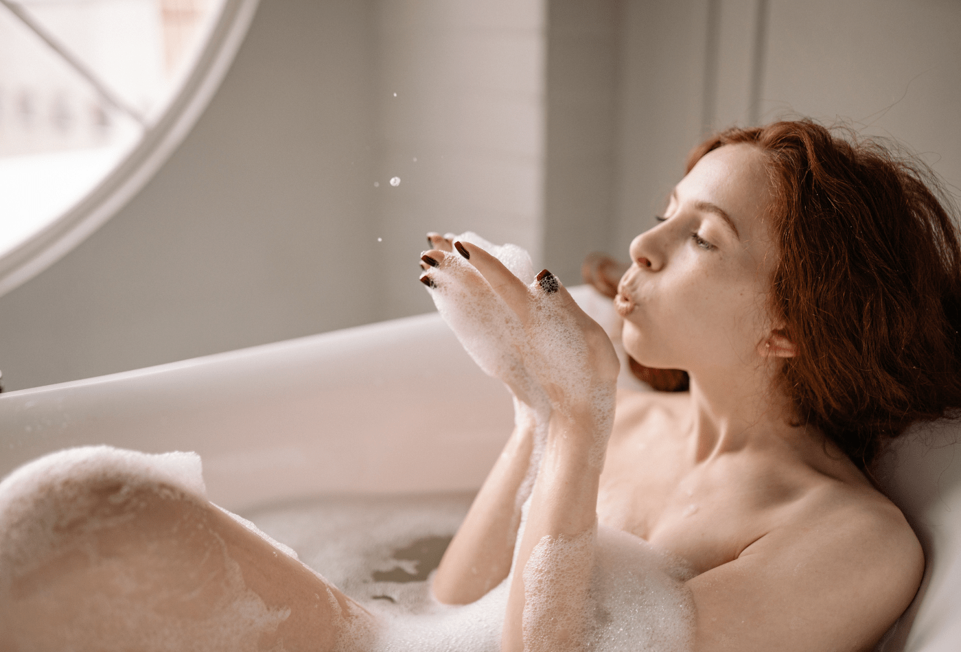 women in bath blowing bubbles 