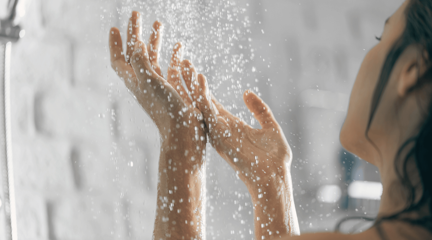 woman with hands in water in shower