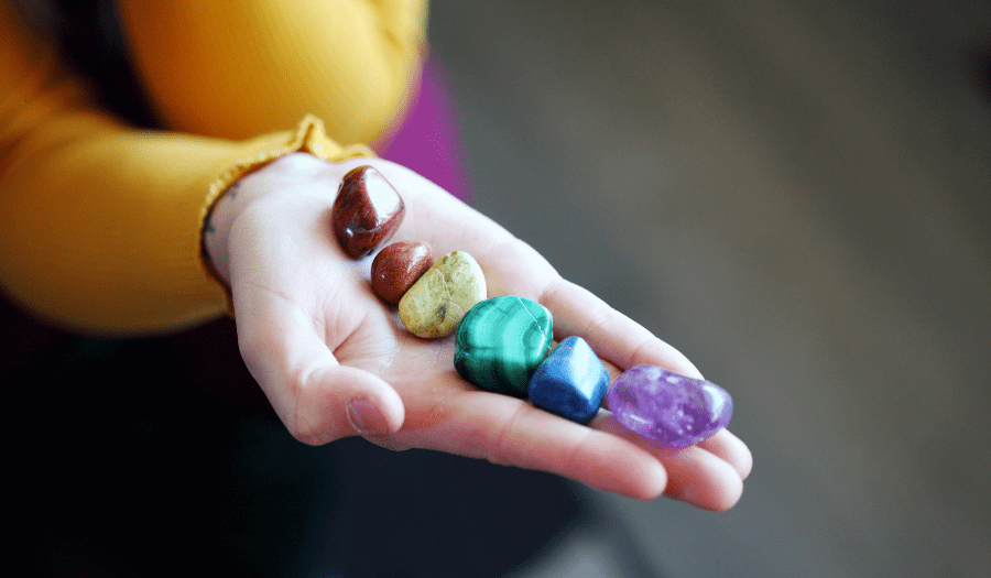 persona sosteniendo cristales de chakra en la palma de su mano