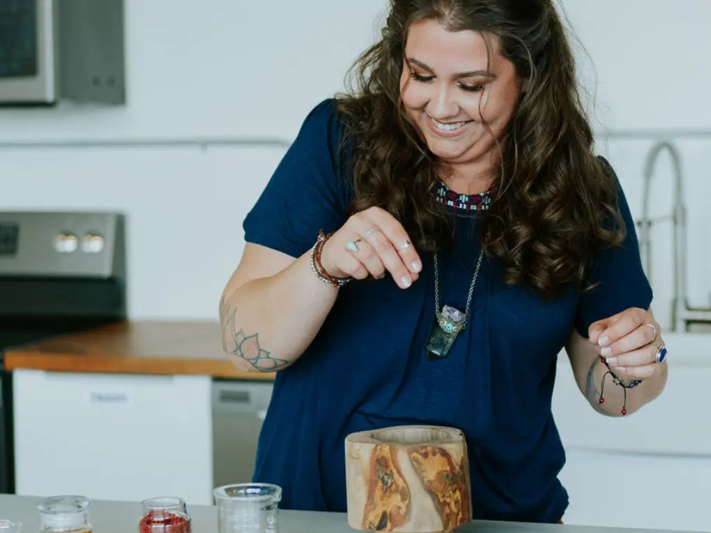 Brittany the founder of Nefertem Tallow skincare sprinkling some ingredients into the wooden bowl