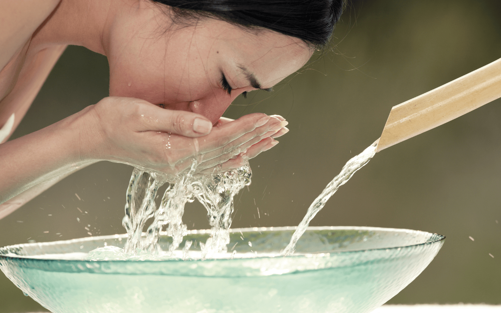 Mujer enjuagándose la cara con agua después de lavarla con jabón Nefertem