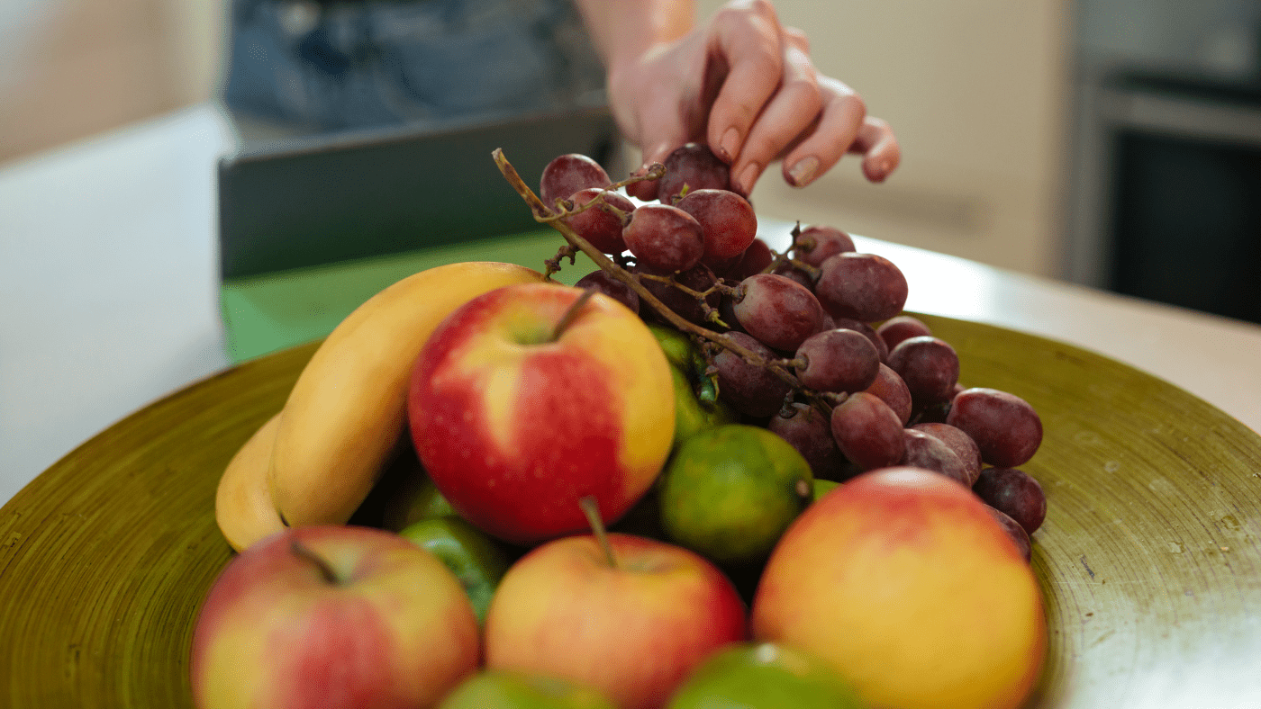 señora agarrando fruta del frutero