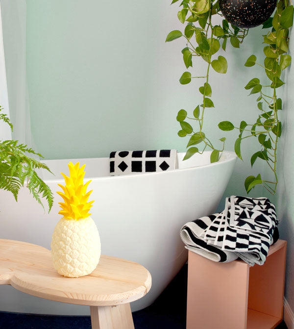 a bathroom scene with bold black and white towels, a bench, and a pineapple nightlight
