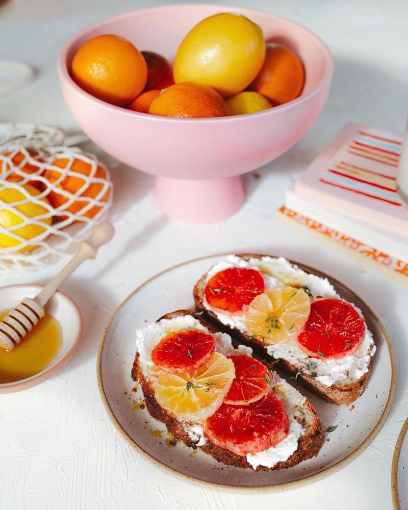 a pink bowl filled with citrus fruit