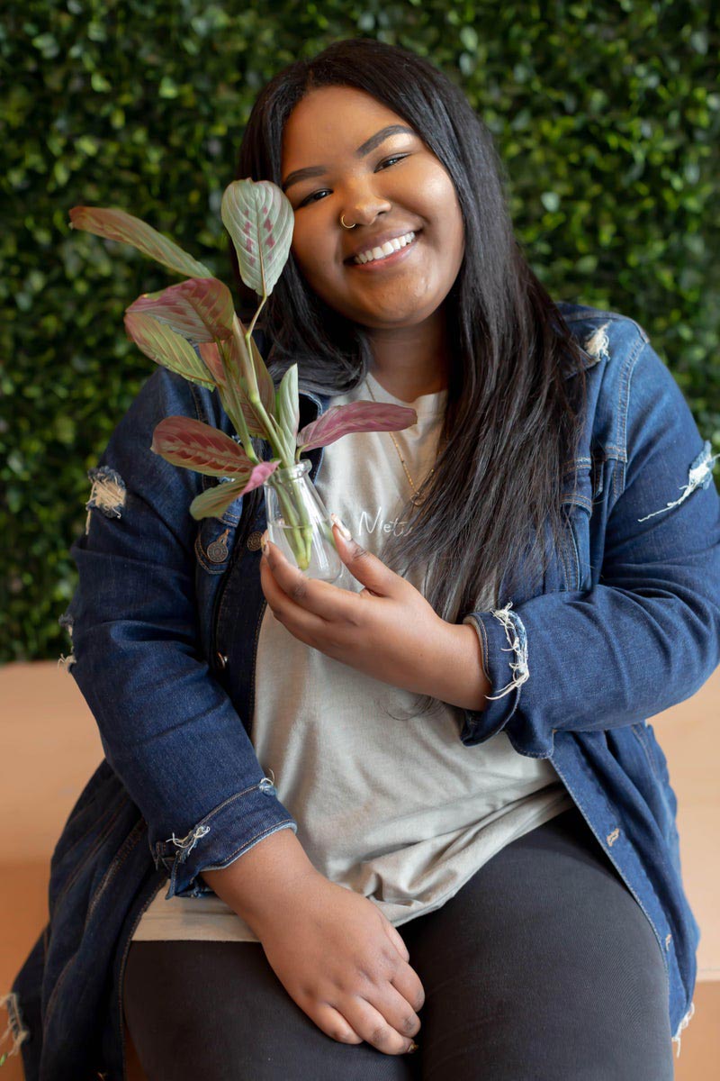 Mikayla Melson, holding a plant, and smiling