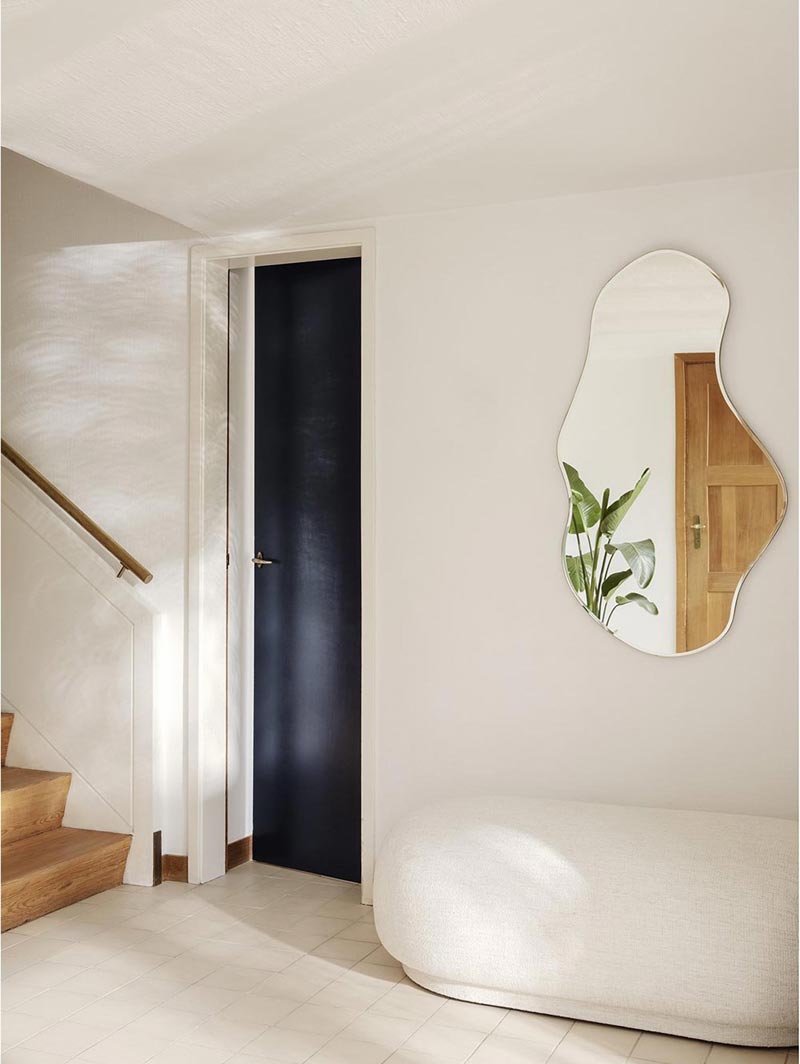 a curvaceous mirror in a plain hallway