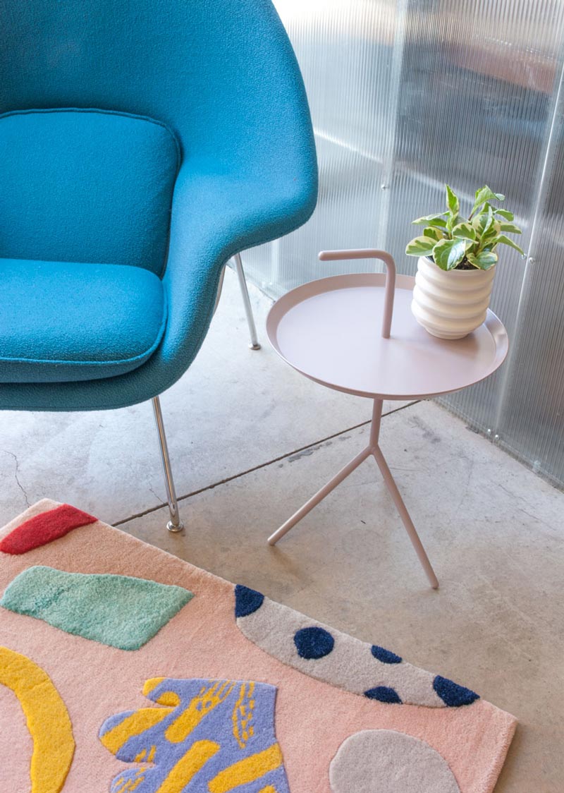 a turquoise lounge chair, a multi color rug and a lavender side table