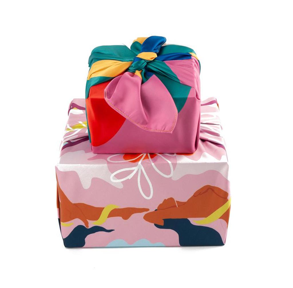 a stack of two presents, wrapped in vivid fabric in pinks and teals and browns and yellows