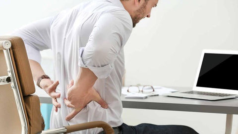 A man with back pain sitting on a chair