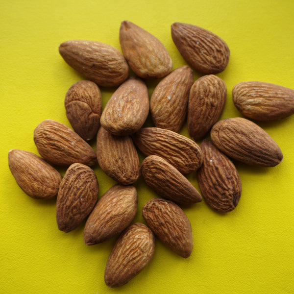 raw almonds with a yellow background