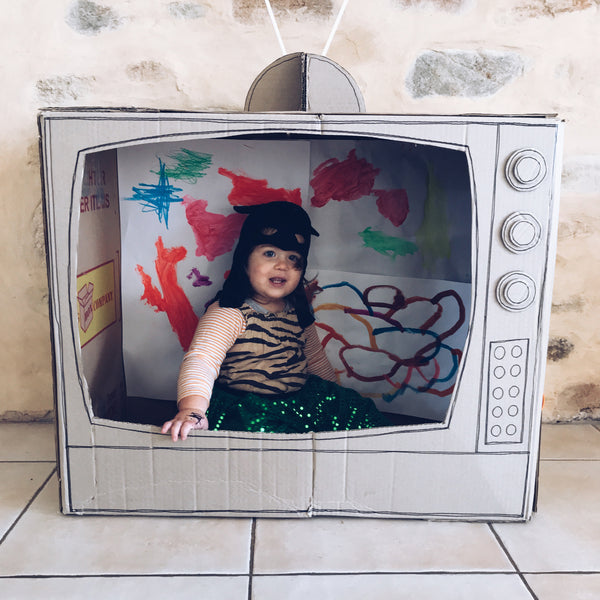 child playing inside a cardboard box TV set