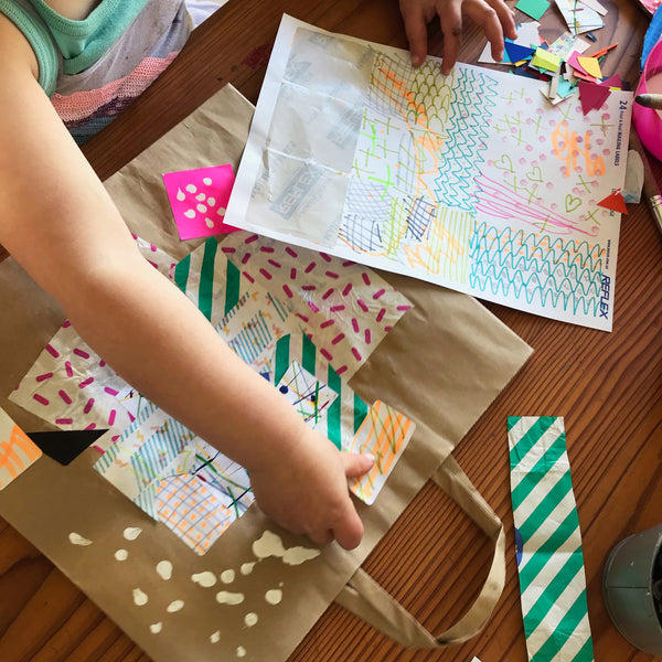child adding stickers to a paper bag collage