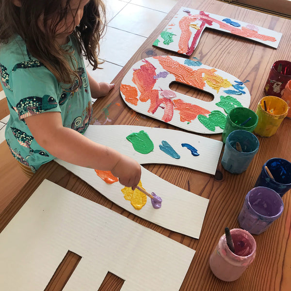 Child painting large cardboard letters