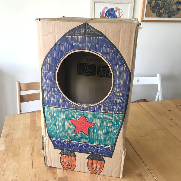 A rocket dress up costume for kids made from a cardboard box