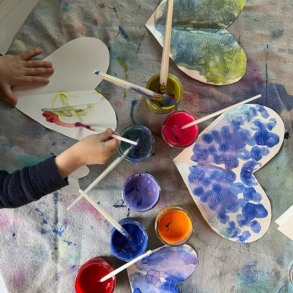 Child painting colourful hearts