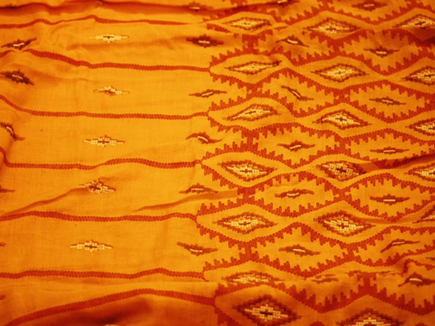An orange and red sari ready to be sewn into sari clothing. 