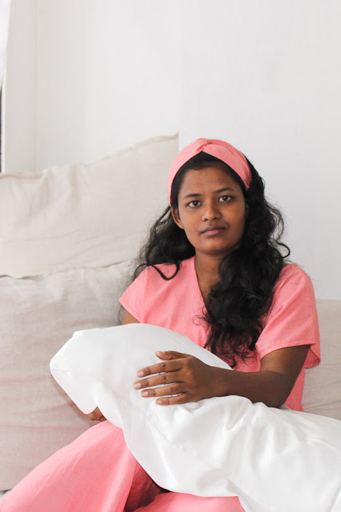 Model wearing Coral Pink Rest Collection holding the Peace Silk Pillowcase
