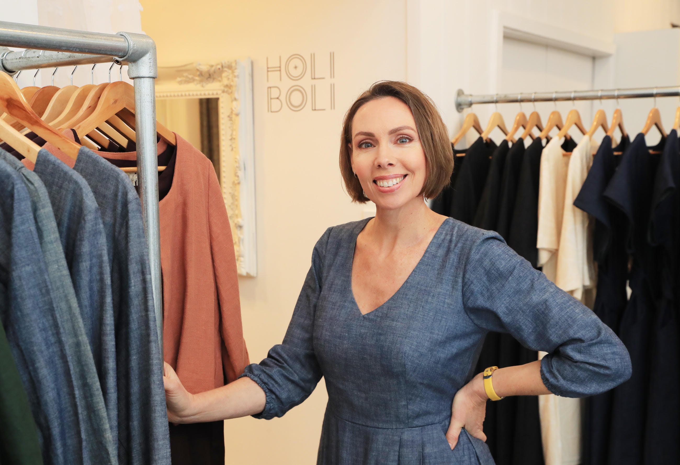 Ana Wilkinson-Gee standing next ethically-made dresses in her workshop