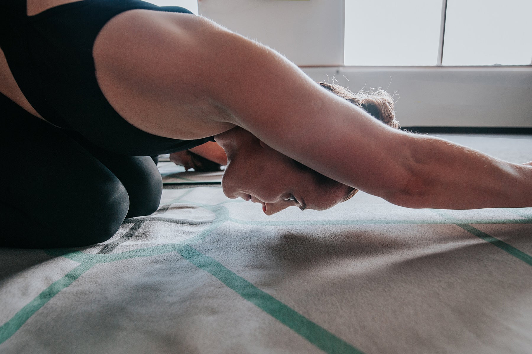 Bikram or hot yoga student doing half tortoise pose ardha kurmasana using the archer hot yoga towel, the best towel for bikram yoga  for alignment