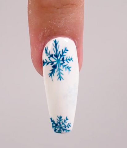 White holiday nails with blue snowflakes accomplished with our Holiday Collection at PLA Inc.  