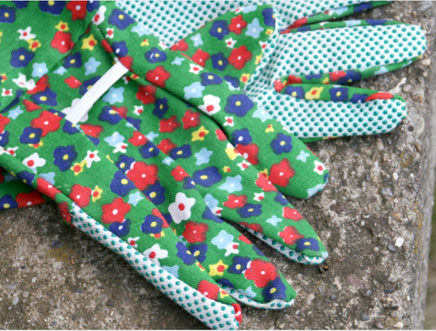 closeup of green, red, and glue gardening gloves laying on pavement