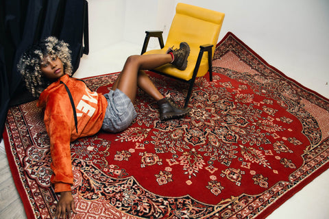 Comment placer un tapis dans votre salon. Dispositions des tapis. Sur cette photo on voit une jeune femme allongé sur se grand tapis de salon
