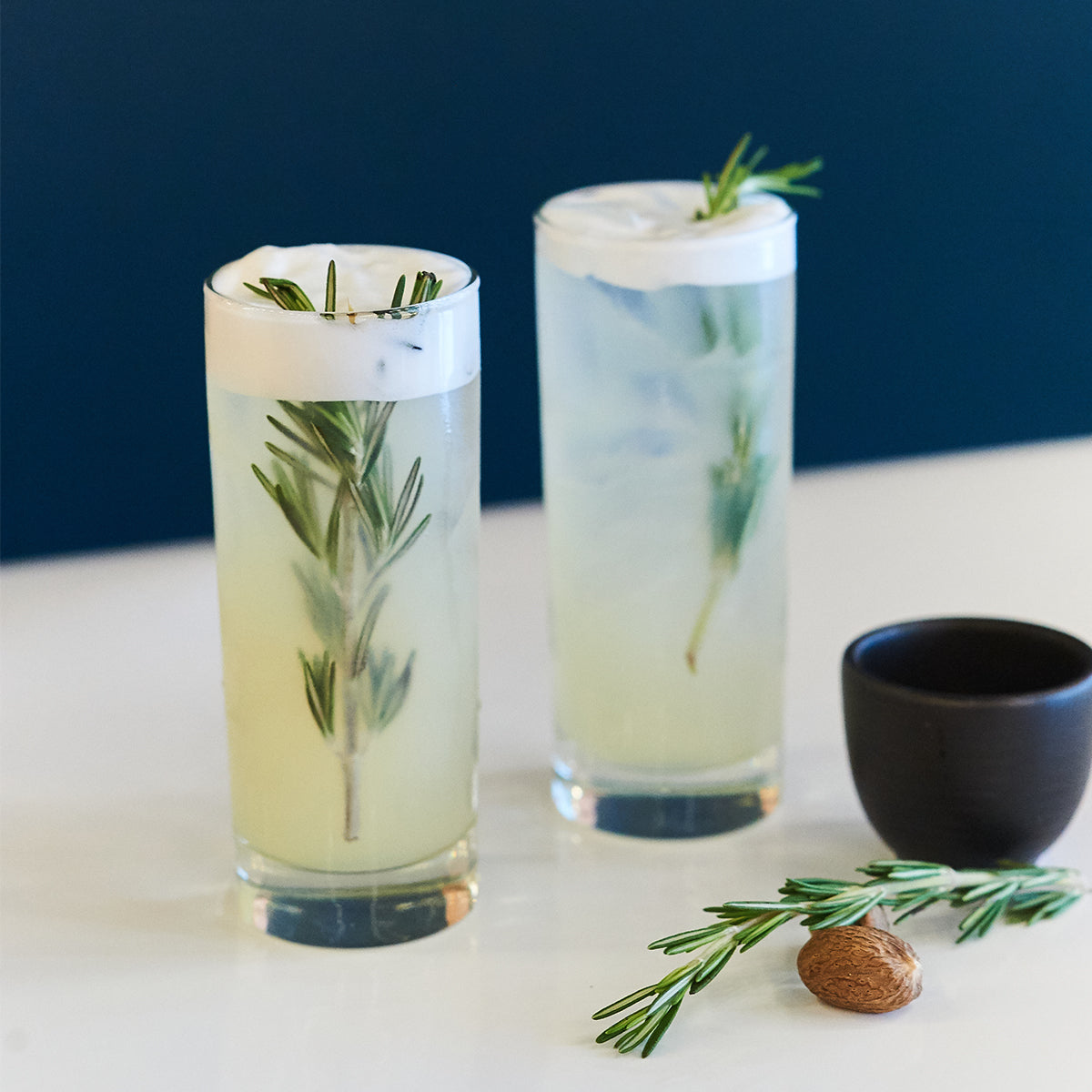 two drinks with rosemary spirgs on top